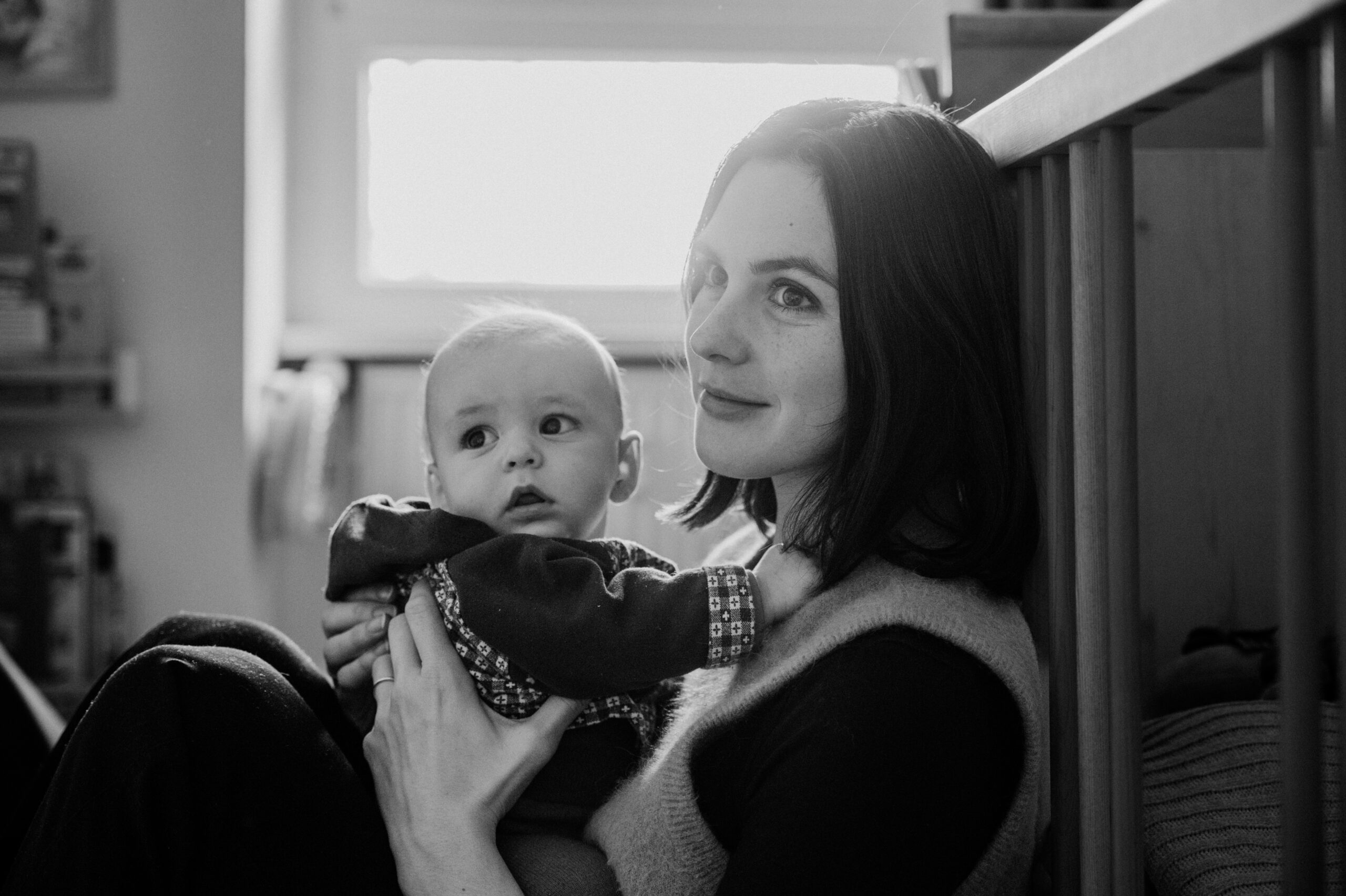 Mutter hält ihr Baby neben dem Kinderbett, Schwarz-Weiß-Aufnahme